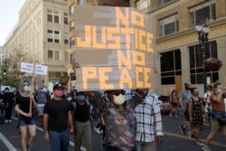 A woman holds up a sign in Oakland, Calif., June 4, 2020, during a protest over the death of George Floyd, who died May 25 after being restrained by police in Minneapolis.