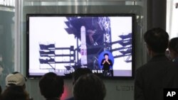 Warga Korea Selatan menyaksikan program televisi di sebuah stasiun kereta api di Seoul, yang menampilkan liputan terkait rencana peluncuran roket Unha-3 Korea Utara, Minggu (8/4).