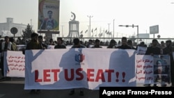 People hold a banner reading 'Let us eat' before marching on the street during a protest in Kabul on Dec. 21, 2021, as the country struggles with a deep economic crisis.