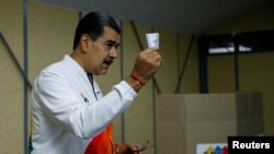 Venezuela's President Nicolas Maduro shows his ballot during an electoral referendum over Venezuela's rights to the potentially oil-rich region of Esequiba, which has long been the subject of a border dispute between Venezuela and Guyana, in Caracas, Venezuela, Dec. 3, 2023