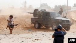 FILE - A journalist covers the frontline during clashes between forces loyal to strongman Khalifa Haftar and fighters loyal to the Libyan internationally-recognized Government of National Accord, south of Tripoli, May 25,2019. 