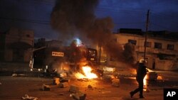 Riot police walk past street fires lit by protesters in Dakar, Senegal, January 31, 2012.