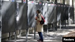 A woman looks at official European election posters outside a polling station in Paris, France, May 13, 2019.