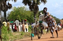 FILE - A refugee from South Sudan transports food she received from the World Food Program (WFP) in Palorinya settlement camp for distribution, in Moyo district northern Uganda.