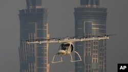 FILE - A Volocopter prototype flies in front of the two hotel towers during a test flight of pilotless taxis in Dubai, United Arab Emirates, Sept. 26, 2017. The ride-hailing company Uber says, Nov. 8, 2017, it has signed a deal with the U.S. space agency NASA to develop a fleet of flying vertical takeoff and landing taxis by the end of the decade.