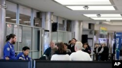 Passengers stand in line as they wait to pass through a Transportation Security Administration checkpoint at LaGuardia airport, Jan. 7, 2019, in New York.