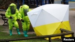 FILE - The forensic tent, covering the bench where Sergei Skripal and his daughter Yulia were found, is repositioned by officials in protective suits in the center of Salisbury, Britain, March 8, 2018.