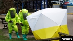 Tenda forensik, yang menutupi bangku di mana Sergei Skripal dan putrinya Yulia ditemukan, diatur posisinya oleh petugas yang mengenakan pakaian pelindung di tengah kota Salisbury, Inggris, 8 Maret 2018.