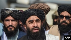 Taliban spokesman Zabihullah Mujahid, center, addresses a media conference at the airport in Kabul on Aug. 31, 2021.