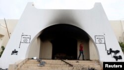 A man walks at the headquarters of Islamist militant group Ansar al-Sharia after it was set on fire by protesters after clashes between members of the group and a Libyan army special forces unit in the Ras Obeida area in Benghazi, Nov. 25, 2013.