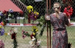 A woman places flowers on a fence at the waterfront in Whakatane, New Zealand, Dec. 11, 2019.