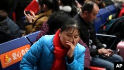 A woman reacts as she waits for her train at the South Train Station in Beijing, Feb. 1, 2019. China is greeting the lunar new year with celebrations and a travel rush that will see an estimated 3 billion trips by people around the country.