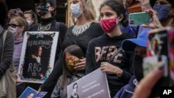 Ella Frederack, center, caresses the face of her daughter Lee, 7, during a public remembrance to honor the life and legacy of U.S. Supreme Court Justice and former Brooklynite Ruth Bader Ginsburg, outside Brooklyn's, Municipal Building, Sunday Sept. 20, 2020. (AP)