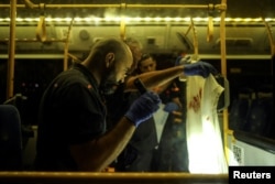 Seorang petugas polisi Israel memeriksa kain berlumuran darah di dalam bus menyusul insiden di Yerusalem 14 Agustus 2022. (Foto: REUTERS/Ammar Awad)