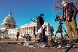 FILE - Members of the news media survey damaged equipment outside the U.S. Capitol a day after supporters of U.S. President Donald Trump stormed and occupied the Capitol in Washington, Jan. 7, 2021.