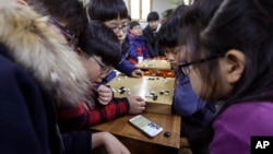 Children watch a smartphone screen showing the live broadcast of the Google DeepMind Challenge Match between Google's artificial intelligence program, AlphaGo, and South Korean professional Go player Lee Sedol, at Lee's Baduk Center in Seoul, South Korea.