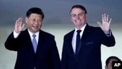 China's President Xi Jinping, left, and Brazil's President Jair Bolsonaro wave to reporters upon Xi's arrival for a bilateral meeting on the sidelines of the 11th BRICS Summit, at Itamaraty Palace, in Brasilia, Brazil, Nov. 13, 2019.