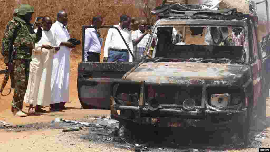 Des agents de sécurité et des membres du gouvernement inspectent une voiture de police qui a été brûlée lors d&#39;une attaque contre un convoi escortant le gouverneur de la région de Mandera Ali Roba près de la ville de Mandera, 13 Mars 2015.