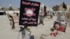 FILE - Religious flags, photographs and tributes to victims of a suicide bombing of a Shi'ite mosque are displayed at a cemetery in al-Qudeeh, Saudi Arabia, May 30, 2015.