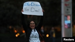 FILE - A demonstrator, part of a group blocking traffic, demands action by the federal government on the Deferred Action for Childhood Arrivals program in San Diego, Calif., Dec. 4, 2017. 