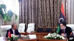 FILE - Turkey's Foreign Minister Mevlut Cavusoglu, right, and Fayez Sarraj, the head of Libya's internationally-recognized government, speak during a meeting in Tripoli, Libya, June 17, 2020.