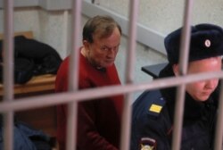 Russian historian and professor Oleg Sokolov, who is accused of murdering his girl friend and former student, is escorted inside a court building in Saint Petersburg, Russia, Nov. 11, 2019.