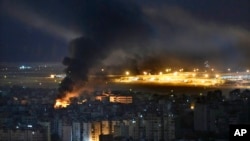 Flames and smoke rise from an Israeli airstrike, as Rafik Hariri international airport is seen in the background, in the southern suburbs of Beirut, Lebanon, Oct. 20, 2024. 