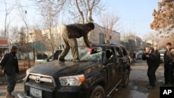 An Afghan driver removes a broken windshield of his car following the Friday's suicide attack and shooting in Kabul, Afghanistan, Saturday, Jan. 18, 2014.