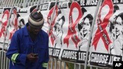 FILE - A man talks on a mobile phone as he walks past World AIDS Day banners in Johannesburg, South Africa, Dec. 1, 2014.