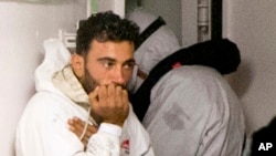Tunisian navigator Mohammed Ali Malek, seen in this April 20, 2015, photo, and one of the survivors of the boat that overturned off the coast of Libya, wait to disembark from Italian Coast Guard ship Bruno Gregoretti, at Catania Harbor, Italy. A court in Italy today has convicted Malek of being responsible for the deaths of hundreds of migrants in one of the worst Mediterranean disasters since World War II.