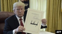 លោក​ប្រធានាធិបតី​ ដូណាល់ ត្រាំ លើក​ឯកសារ​ក្នុង​ព្រឹត្តិការណ៍​ចុះ​ហត្ថលេខា​កាត់​បន្ថយ​ពន្ធដារ​នៅ​សេត​វិមាន។