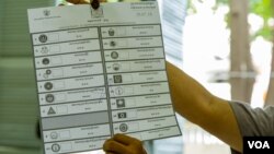 មន្ត្រីរៀបចំការបោះឆ្នោតលើកបង្ហាញសន្លឹកឆ្នោតមួយសន្លឹក​​ បន្ទាប់ពីការិយាល័យ​បោះឆ្នោតនៅទូទាំងប្រទេសបានបិទ នៅសង្កាត់បឹងកេង​កង២ ខណ្ឌ​ចំការមន រាជធានីភ្នំពេញ​ នៅ​ថ្ងៃអាទិត្យ​ ទី២៩ ខែកក្កដា​ ឆ្នាំ២០១៨។ (ខាន់ សុគុំមនោ/VOA)