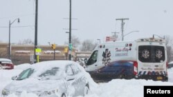 눈 폭풍이 강타한 뉴욕주 버펄로에서 26일 눈 속에 파묻힌 승용차 옆으로 구급차가 지나가고 있다. 