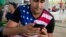 Cuban migrant wearing a t-shirt with a US flag design, uses his cell phone at a shelter in La Cruz, Costa Rica, border with Nicaragua. 