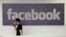 FILE - A Facebook employee walks past a sign at Facebook headquarters in Menlo Park, California, March 15, 2013.