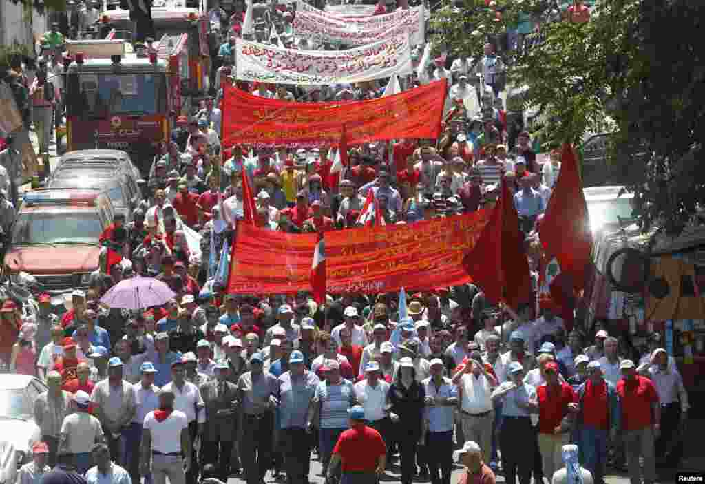 Lebanese leftist activists wave flags as they march during a demonstration to mark May Day along a street in Beirut, May 1, 2013.