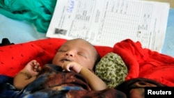 Un enfant somalien repose à côté de sa carte de maternité de l'hôpital du Comité international de secours au camp de réfugiés de Dadaab au Kenya.