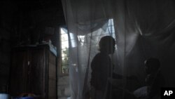 A mother and her child sit on a bed covered with a mosquito net near Bagamoyo, 70 km north of Tanzanian capital Dar es Salaam, 30 Oct 2009