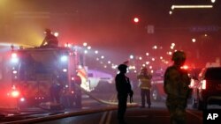 The National Guard standby as firefighters extinguish a blaze at a gas station Friday, May 29, 2020, in Minneapolis. Protests continued following the death of George Floyd, who died after being restrained by Minneapolis police officers on Memorial Day. (AP Photo/Julio Cortez)