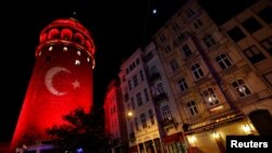 Sebuah bendera Turki diproyeksikan ke Menara Bersejarah Galata di Istanbul (12/12) untuk menghormati para korban ledakan di stadion sepakbola kota itu, Sabtu (10/12). 