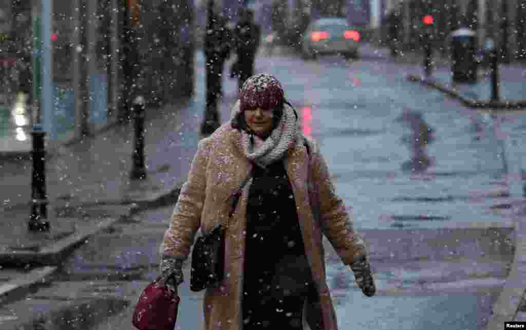 A pedestrian walks along a street during the first snow fall of the season in Rickmansworth, Britain.