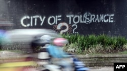 Seorang pengendara melewati grafiti yang menyerukan toleransi di Yogyakarta. (Foto: AFP)