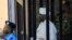 FILE - Sudan's former president Omar Hassan al-Bashir stands guarded inside a cage at the courthouse where he is facing corruption charges, in Khartoum, Sudan, Aug. 19, 2019.