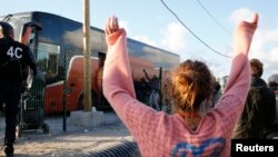 A volunteer waves to migrant minors in a bus during their transfer by French authorities to reception centers across the country at the end of the dismantlement of the camp called "the Jungle" in Calais, France, Nov. 2, 2016. 