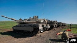 An Israeli soldier sits by shells laid behind Merkava battle tanks holding position near Moshav Kidmat Tzvi in the Golan Heights on Dec. 25, 2020.