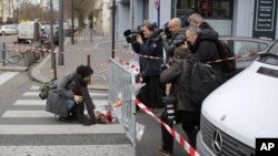 Watched by the media a woman lays a flower tribute at the site of the attack on a kosher market in Paris, France, Saturday, Jan. 10, 2015. (AP Photo/Laurent Cipriani)
