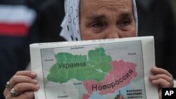 ស្រ្តី​ម្នាក់​កាន់​ផែនទី​ប្រទេស​អ៊ុយក្រែន​ចែក​ជា​ពីរ​ផ្នែក នៅ​អំឡុង​ពេល​ដង្ហែ​ក្បួន​សន្តិ​ភាព​មួយ​នៅ​ក្រុង Donetsk ភាគខាង​កើត​ប្រទេស​អ៊ុយក្រែន។ ការ​ព្រួយ​បារម្ភ​ពី​​រុស្ស៊ី​ជំរុញ​ឲ្យ​ប្រទេស​ជិត​ខាង​រុស្ស៊ី​​ងាក​ទៅ​រក​អង្គការ​ណាតូ។ 