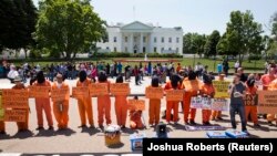 Para aktivis memakai seragam oranye, melakukan unjuk rasa di depan Gedung Putih menandai 100 hari aksi mogok makan para narapidana di Guantanamo (17/5)