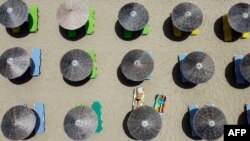 FILE - A woman sunbathes at Falaserna (Phalasarna) beach on the western coast of Crete island on May 15, 2021. 