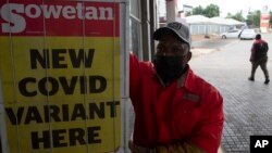 A gas station attendant stands next to a newspaper headline in Pretoria, South Africa, Nov. 27, 2021.